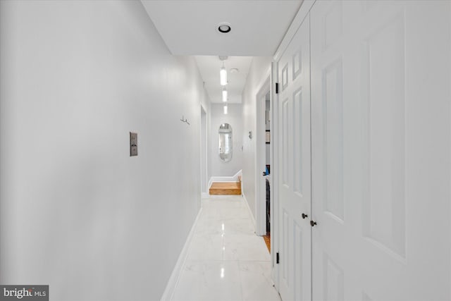 hallway with baseboards and marble finish floor