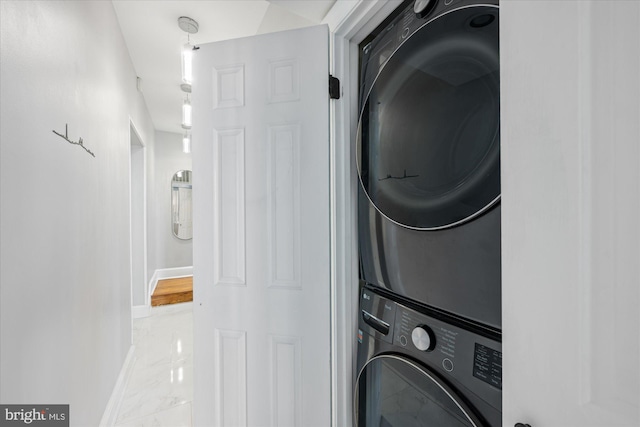 laundry area featuring laundry area, stacked washer / dryer, baseboards, and marble finish floor