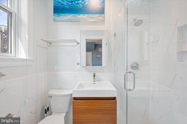 bathroom with a marble finish shower, plenty of natural light, toilet, and vanity