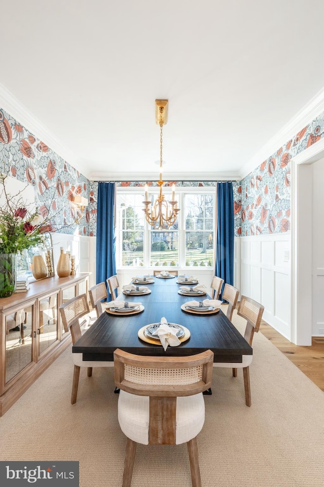 dining space with a notable chandelier, light wood-style flooring, ornamental molding, wainscoting, and wallpapered walls