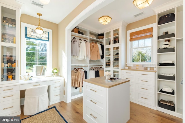 walk in closet with light wood-style flooring, visible vents, and built in study area