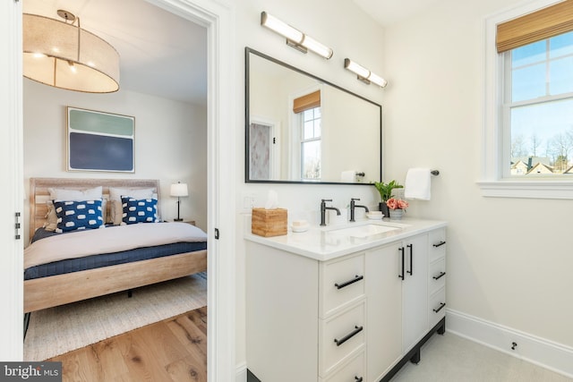 bathroom with plenty of natural light, wood finished floors, vanity, and baseboards