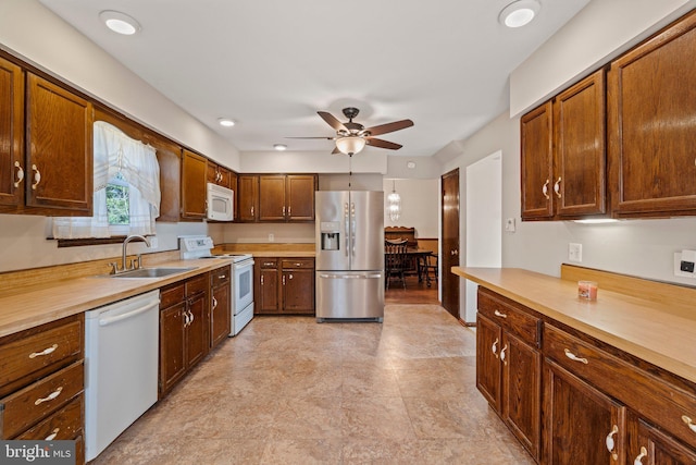 kitchen featuring white appliances, ceiling fan, light countertops, and a sink