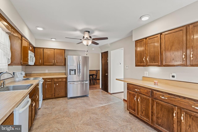 kitchen featuring white appliances, light countertops, a sink, and brown cabinetry