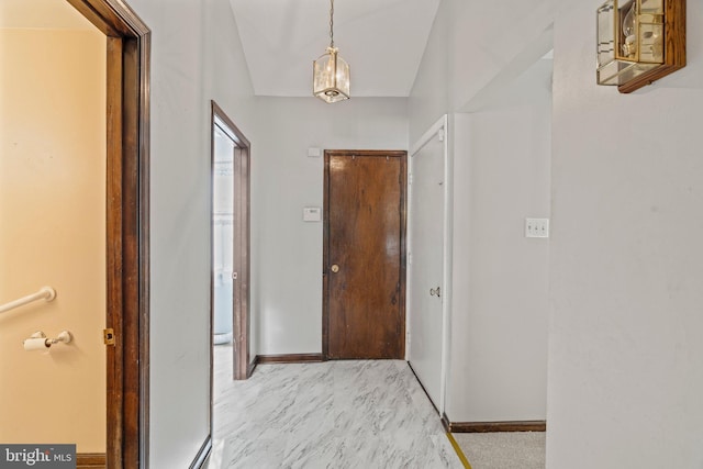 corridor with lofted ceiling and baseboards