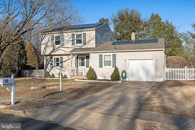 view of front of property featuring concrete driveway, fence, roof mounted solar panels, and an attached garage