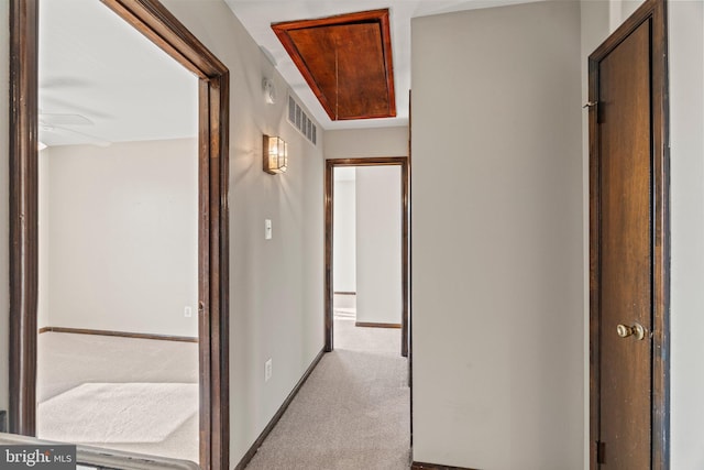 hallway featuring light carpet, visible vents, and baseboards