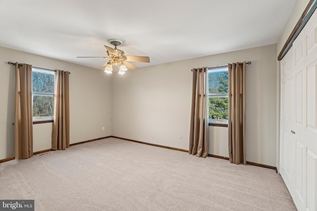 unfurnished bedroom featuring light carpet, multiple windows, a closet, and visible vents