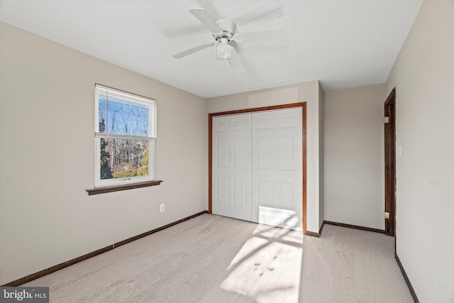 unfurnished bedroom featuring a closet, light carpet, ceiling fan, and baseboards