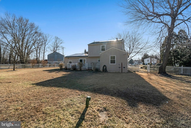 back of property featuring a yard, a chimney, and a fenced backyard