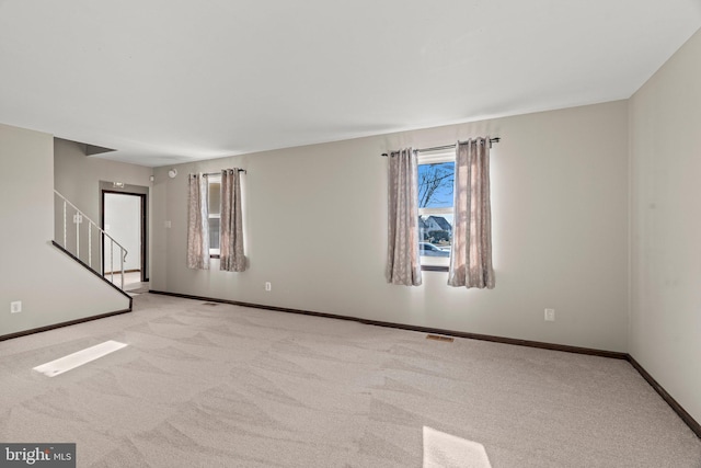 carpeted empty room featuring visible vents, stairway, and baseboards