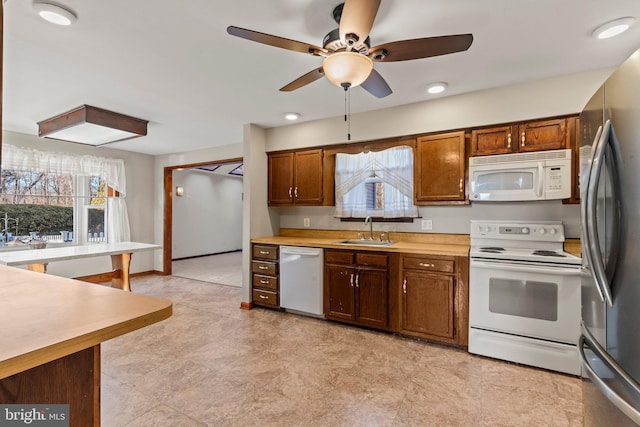 kitchen featuring stainless steel appliances, a sink, light countertops, and baseboards