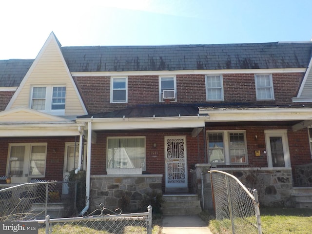 view of property featuring covered porch, brick siding, and a fenced front yard