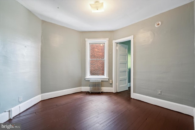 empty room featuring radiator, baseboards, and dark wood-style flooring