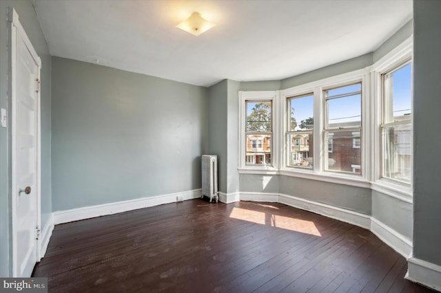 empty room with radiator, dark wood-style floors, and baseboards