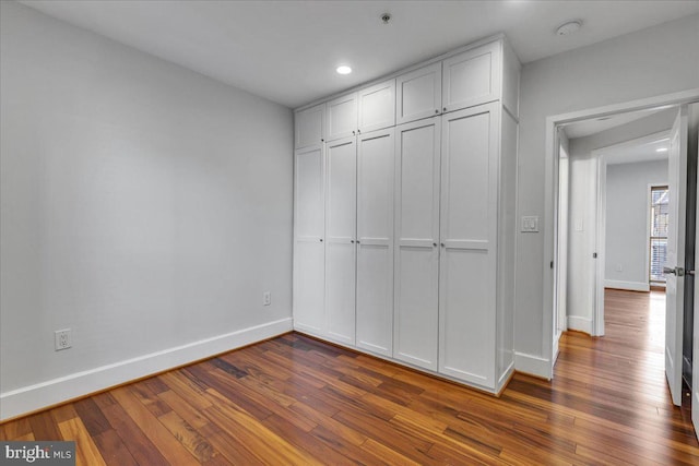 unfurnished bedroom with dark wood-style floors, baseboards, a closet, and recessed lighting