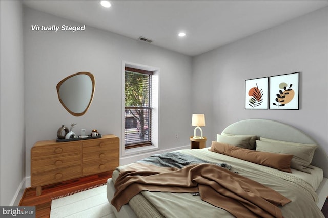 bedroom with baseboards, wood finished floors, visible vents, and recessed lighting