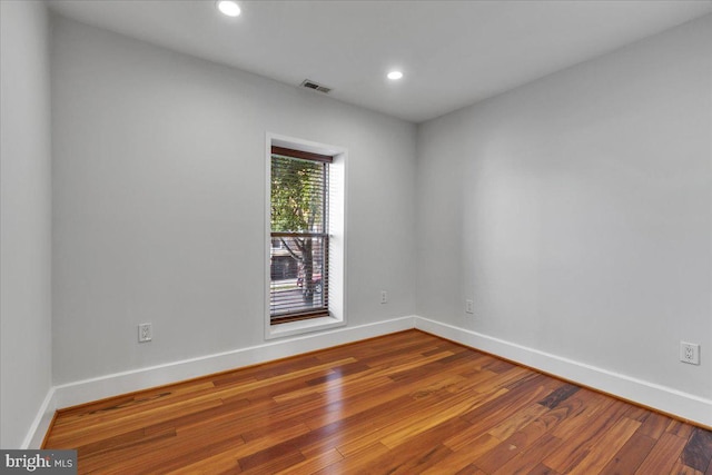 empty room featuring wood-type flooring, baseboards, and recessed lighting