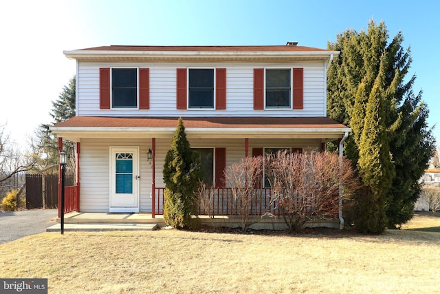 traditional-style house with fence, a porch, and a front yard