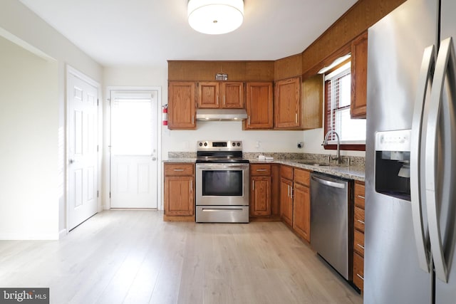246 First Ave, State College, PA 16801 - kitchen featuring light wood-style flooring, under cabinet range hood, a sink, appliances with stainless steel finishes, and brown cabinetry