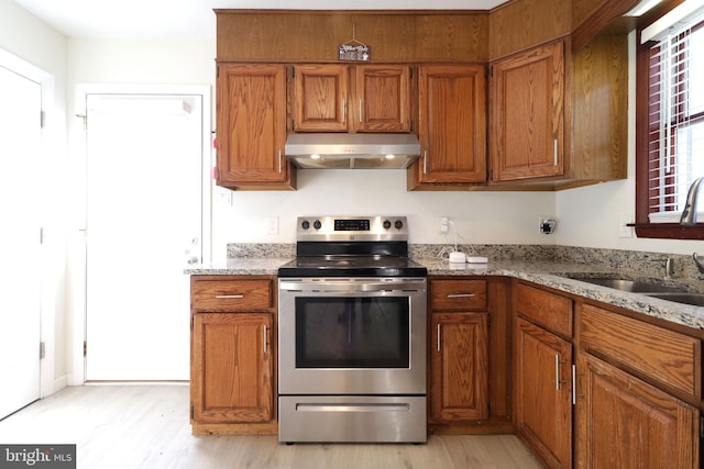 246 First Ave, State College, PA 16801 - kitchen featuring light wood-style flooring, under cabinet range hood, a sink, stainless steel range with electric cooktop, and brown cabinets