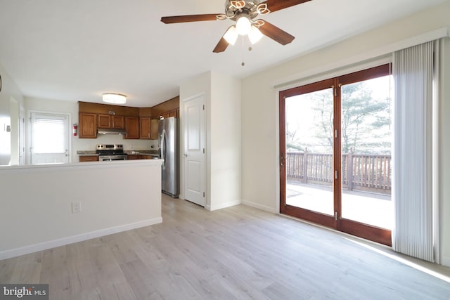 246 First Ave, State College, PA 16801 - kitchen featuring under cabinet range hood, stainless steel appliances, baseboards, light wood-type flooring, and brown cabinetry