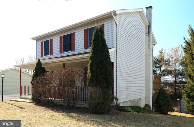 view of side of home featuring covered porch and a chimney