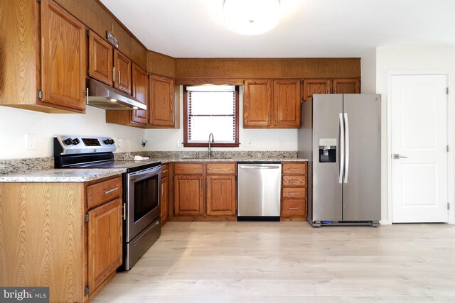 246 First Ave, State College, PA 16801 - kitchen featuring brown cabinets, appliances with stainless steel finishes, a sink, light wood-type flooring, and under cabinet range hood