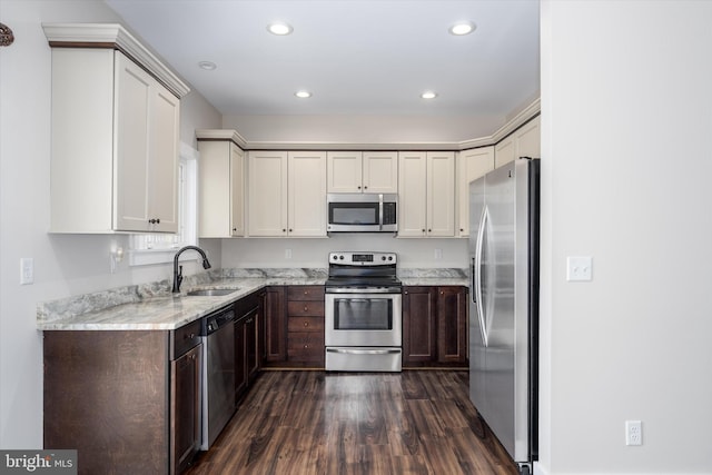 kitchen featuring light stone countertops, dark wood-style floors, recessed lighting, a sink, and appliances with stainless steel finishes