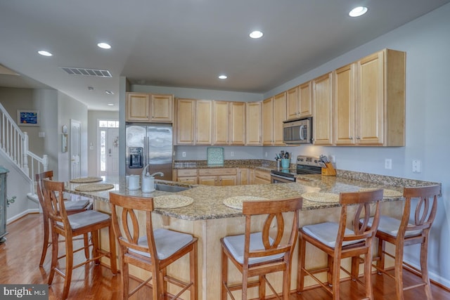 kitchen with light brown cabinets, light wood-style flooring, recessed lighting, stainless steel appliances, and visible vents