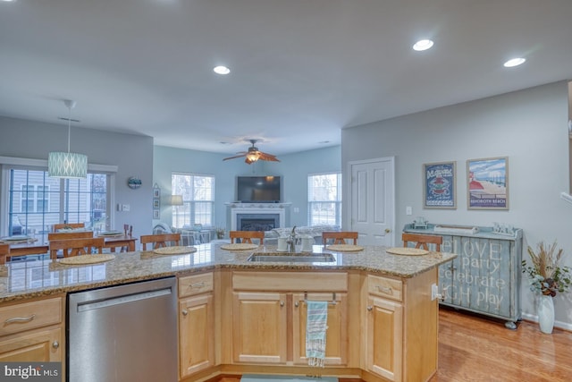 kitchen with open floor plan, stainless steel dishwasher, light wood-style floors, a fireplace, and a sink