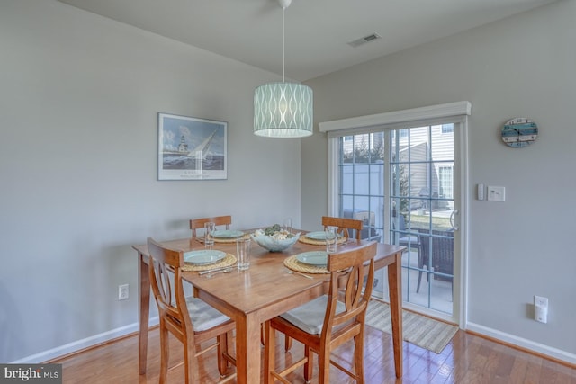 dining space with light wood-style flooring, visible vents, and baseboards