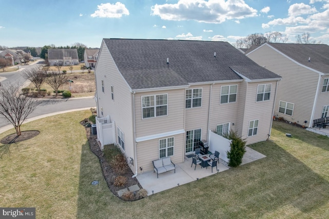 back of property with a patio, a lawn, and roof with shingles