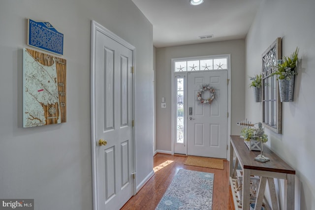 foyer with visible vents, plenty of natural light, baseboards, and wood finished floors