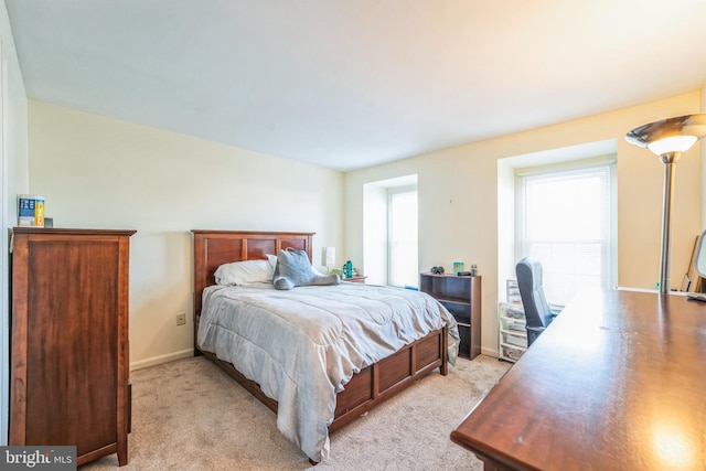 bedroom with light colored carpet and baseboards