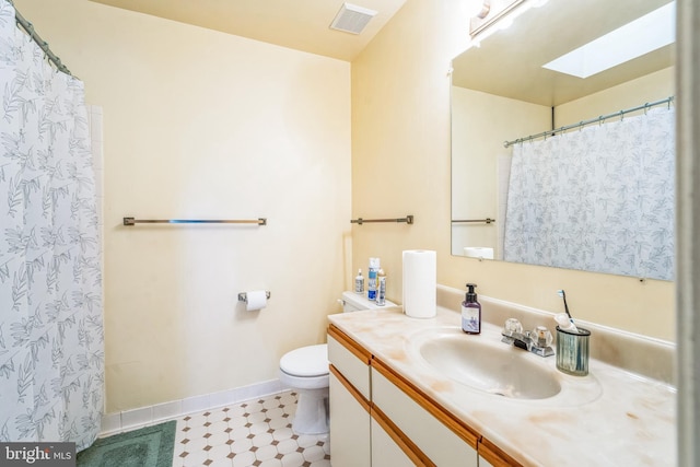 bathroom with visible vents, toilet, a skylight, baseboards, and vanity