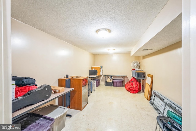 finished basement with tile patterned floors, visible vents, and a textured ceiling