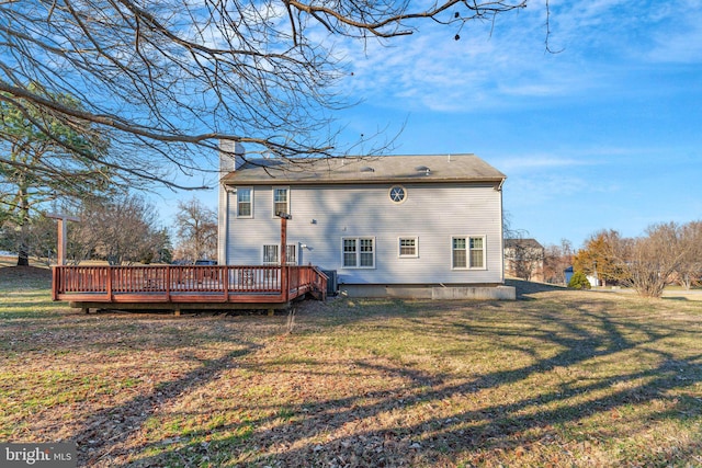 back of property featuring a yard, a chimney, and a wooden deck