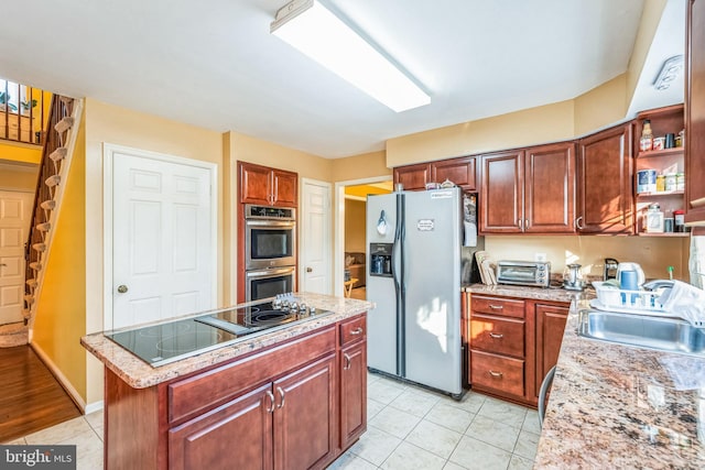 kitchen featuring a sink, a kitchen island, appliances with stainless steel finishes, and light tile patterned floors