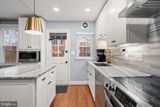 kitchen featuring stainless steel appliances, backsplash, white cabinets, a sink, and exhaust hood