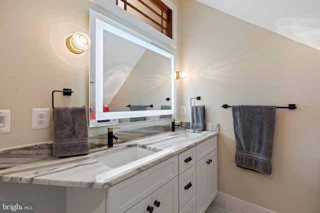 bathroom with double vanity, a sink, and baseboards