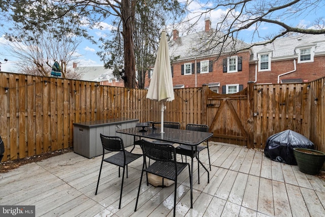 wooden terrace with outdoor dining space, a gate, and fence