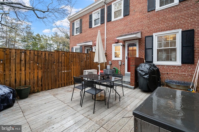 deck with cooling unit, outdoor dining area, a grill, and fence