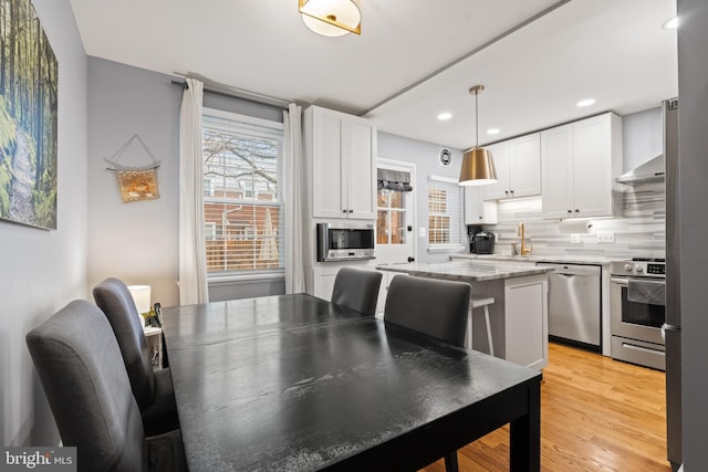 dining area with light wood finished floors and recessed lighting