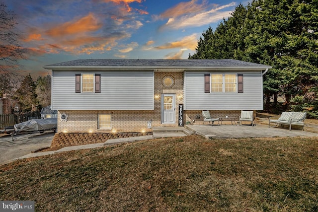 bi-level home featuring brick siding, a front yard, entry steps, a patio area, and fence