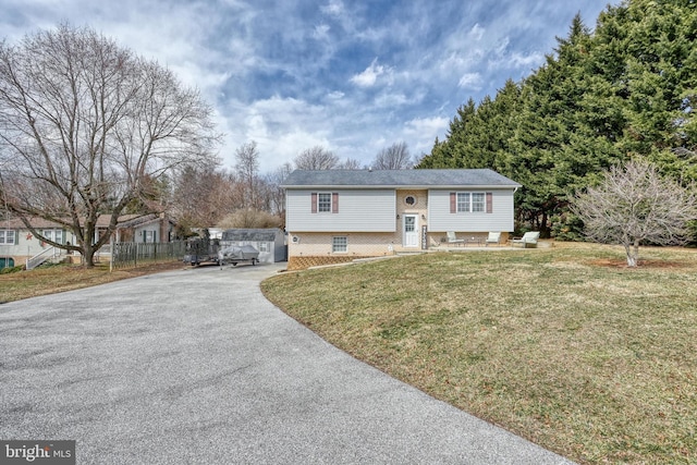 split foyer home with aphalt driveway, a front lawn, and brick siding