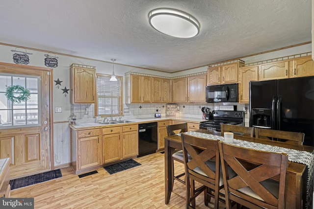 kitchen featuring visible vents, a sink, a textured ceiling, light wood-type flooring, and black appliances