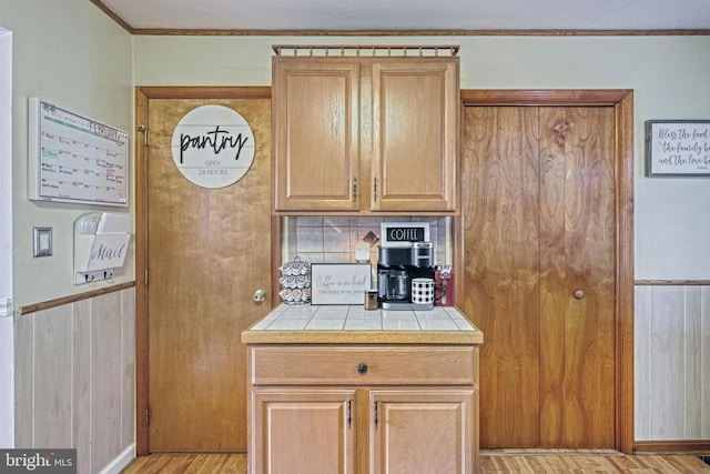 kitchen with backsplash, crown molding, tile countertops, and light wood finished floors