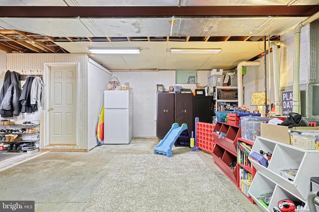 unfinished below grade area with freestanding refrigerator and concrete block wall