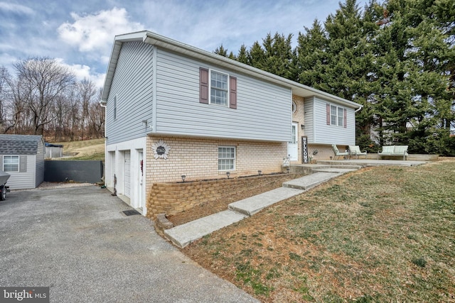 bi-level home with a garage, brick siding, and driveway